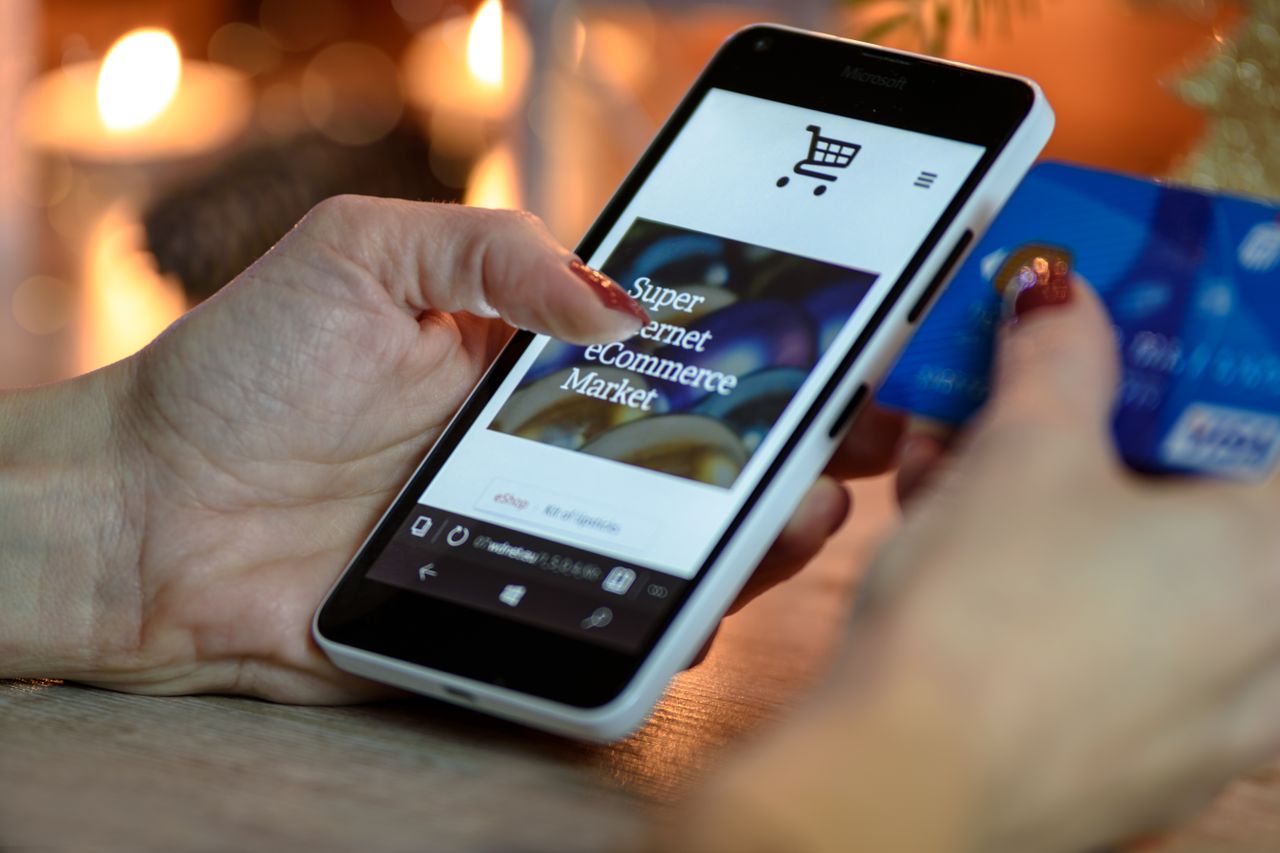 The Art of Drawing Readers In: Your attractive post title goes here Woman using smartphone for online shopping with credit card in hand, festive background lighting.