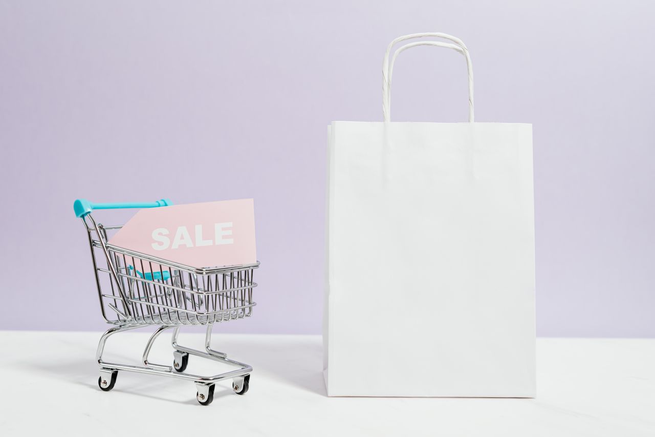 Mastering the First Impression: Your intriguing post title goes here A miniature shopping cart with a sale sign beside a paper bag, perfect for online shopping themes.