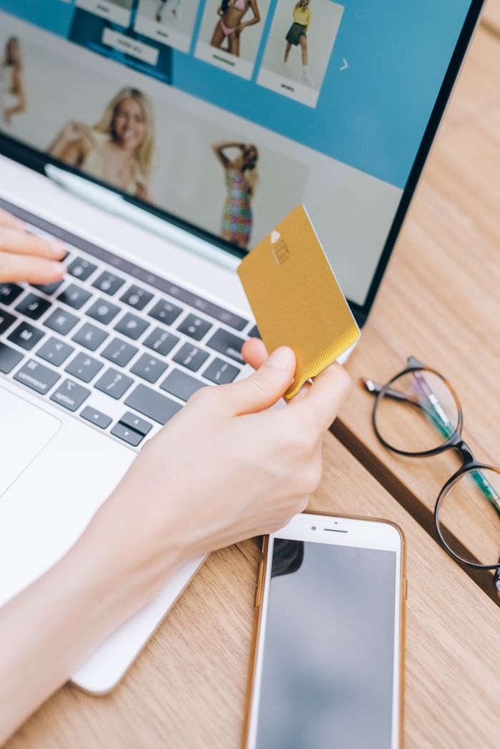 Close-up of woman shopping online using a credit card on a laptop.